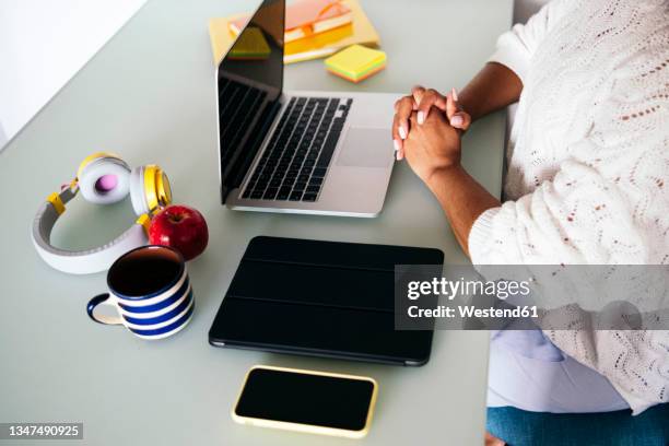 female freelancer with hands clasped at desk - apple laptop stock pictures, royalty-free photos & images