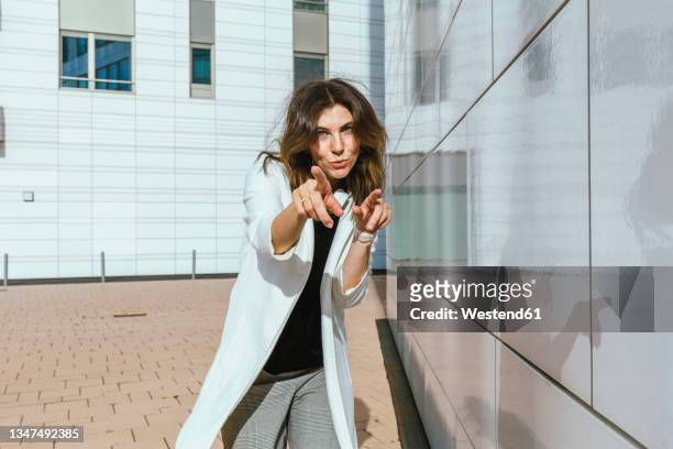 mid adult woman gesturing by wall during sunny day - signaling pathways stock-fotos und bilder
