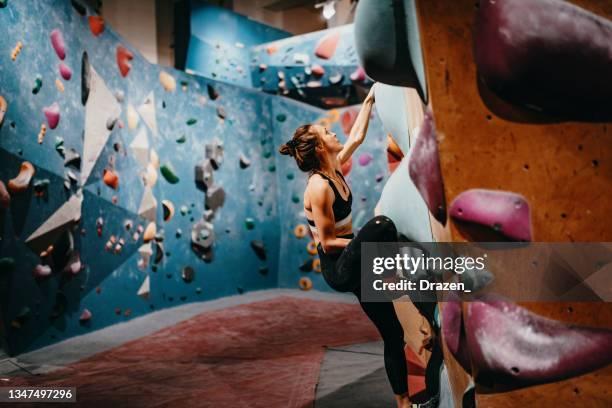 strong woman climbing on boulder walls - rock climbing indoors - bouldern indoor stock pictures, royalty-free photos & images