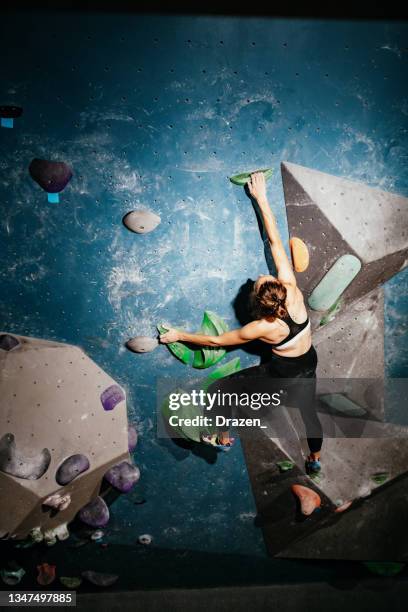 strong woman climbing on boulder walls - rock climbing indoors - bouldern indoor stock pictures, royalty-free photos & images