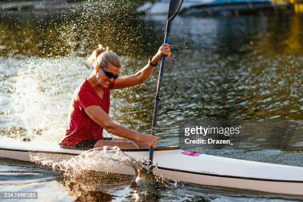 millennial woman kayaking on lake in summer, paddling with strength - row racing stock pictures, royalty-free photos & images