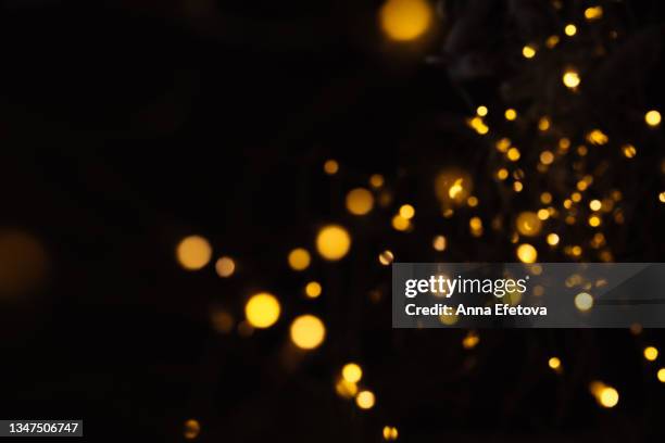 festive black christmas background made of glowing defocused garland with many lights. concept of new year celebration. copy space for your design - desenfocado fotografías e imágenes de stock