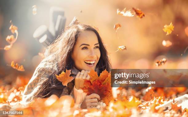 happy young woman in autumn outfit during fall of leaves. - hair fall stock pictures, royalty-free photos & images