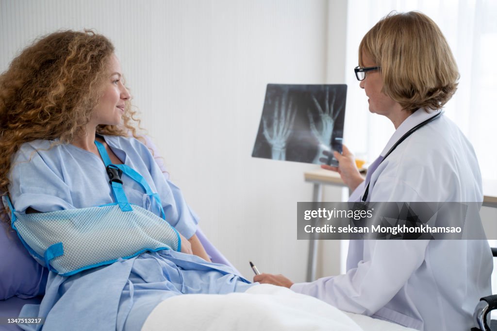 Doctors are translating an X-ray of a woman with a broken arm folded and wrapped around her hand as a patient at the hospital.