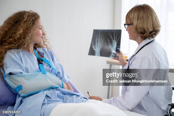 doctors are translating an x-ray of a woman with a broken arm folded and wrapped around her hand as a patient at the hospital. - knochenbruch stock-fotos und bilder