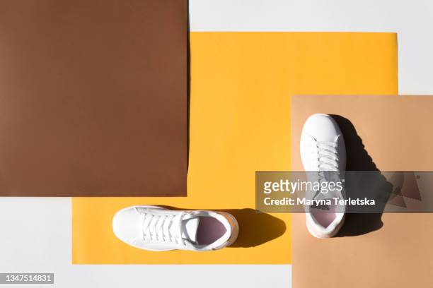 white sneakers on a colored background. - leather training shoes stock-fotos und bilder