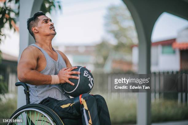 behinderter asiatischer indischer mann im rollstuhl, der morgens mit einem medizinball an die wand im hinterhof seines hauses wirft - einzelner mann über 30 stock-fotos und bilder