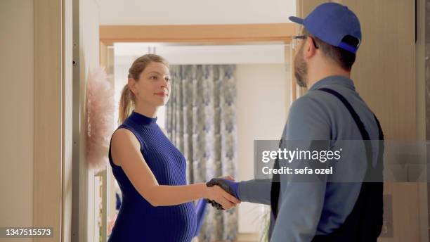 repairman handshake in door - pregnant women greeting stockfoto's en -beelden