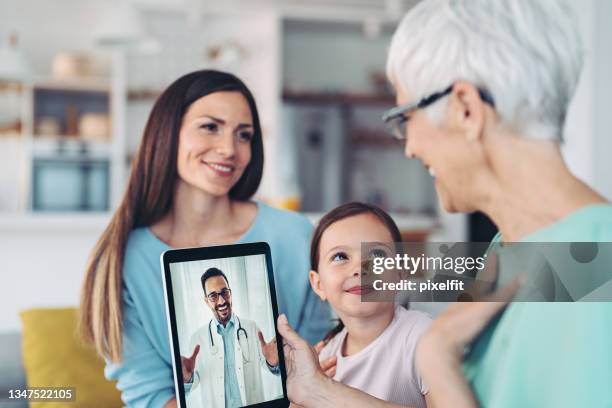 grandmother, mother and daughter in a video call with a doctor - online doctor stock pictures, royalty-free photos & images