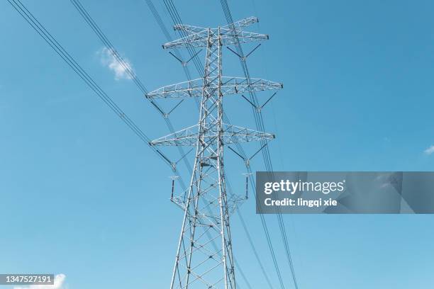 power transmission tower under the blue sky - high voltage sign stock pictures, royalty-free photos & images