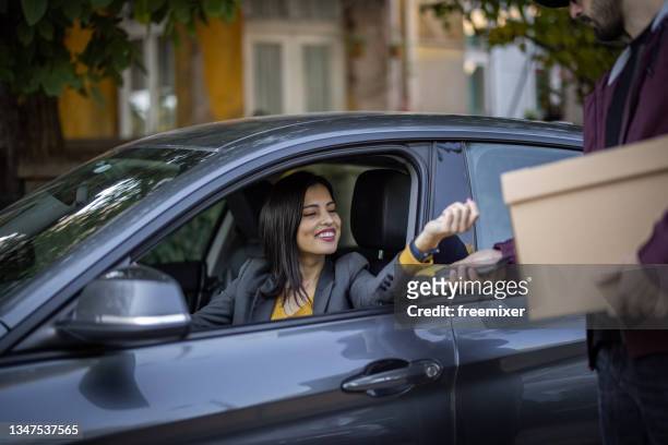 young smiling woman paying with smart watch and picking order from her car at a curb-side pickup - curbside pickup 個照片及圖片檔
