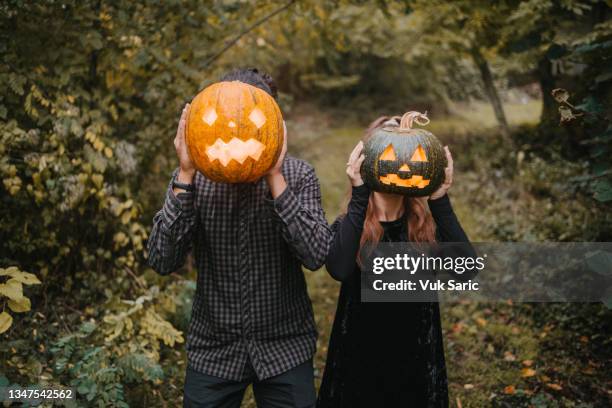 disguised man and woman holding carved pumpkins in front of heads - halloweenlykta bildbanksfoton och bilder