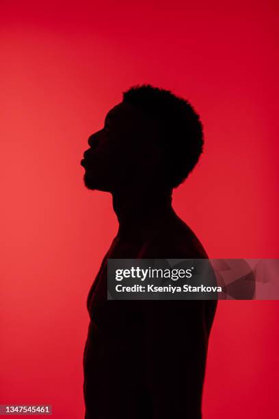 black man in red spotlights in a photo studio on a red background silhouette - studio lighting equipment stock pictures, royalty-free photos & images