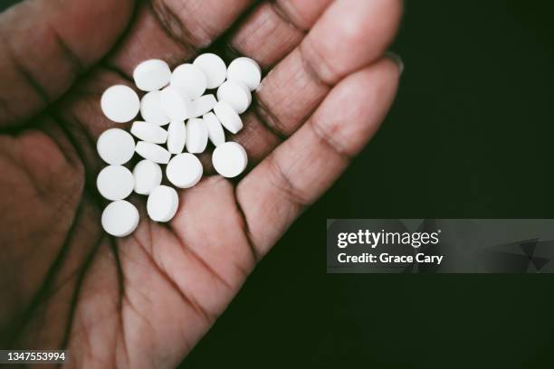 woman holds chalky white pills in palm of hand - aspirina foto e immagini stock
