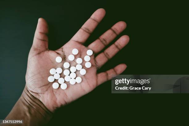 woman holds chalky white pills in palm of hand - acetaminophen stock-fotos und bilder