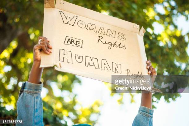 junge frau, die draußen ein frauenrechtsprotestschild hochhält - womens rights stock-fotos und bilder