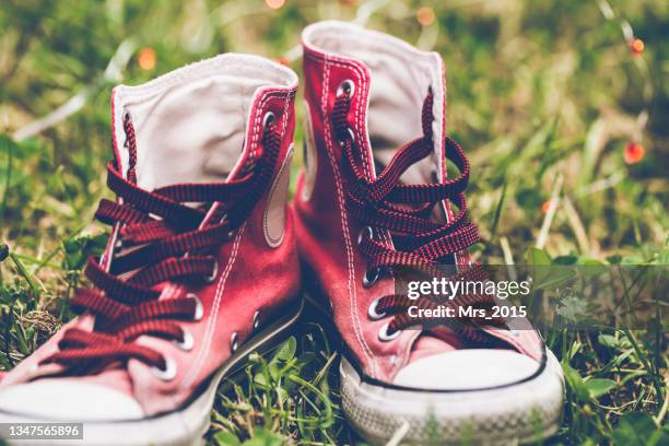 close-up of a pair of high top red sneakers on the grass - shoelace stock-fotos und bilder