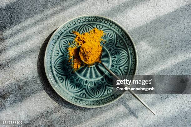 spoonful of turmeric powder on a plate - foodstyling stock-fotos und bilder