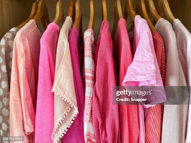 assorted pink tops, blouses, shirts and t-shirts hanging in a wardrobe - hanging blouse stock pictures, royalty-free photos & images