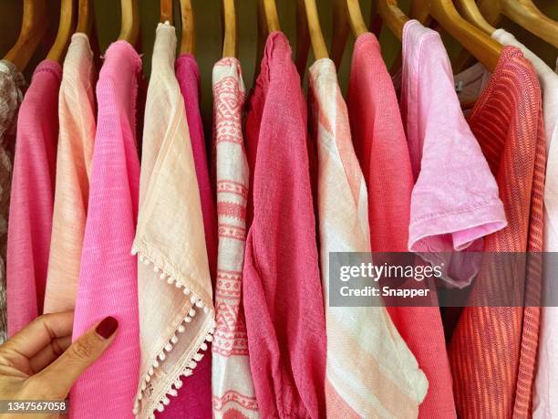 woman choosing which pink top to wear - 衣服掛け ストックフォトと画像