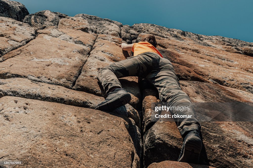 Woman in casual clothes climbing on rock formation without belay