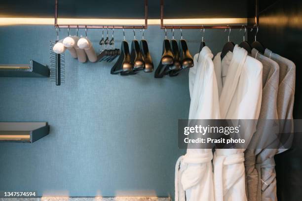 four of gray and white  bathrobe with wooden hangers in wardrobe in bathroom at luxury hotel. - hotel bathroom stock pictures, royalty-free photos & images