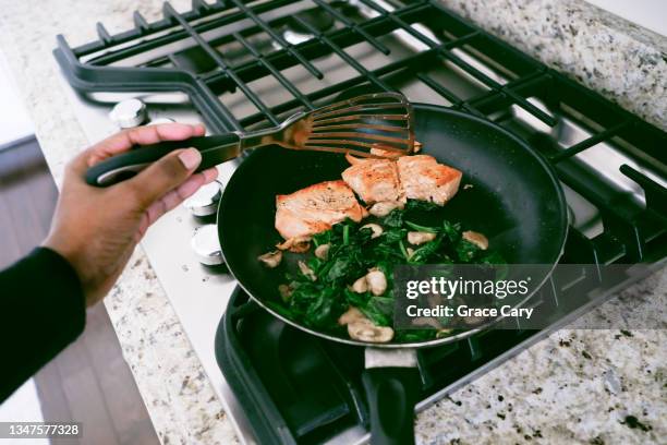 woman cooks salmon with spinach and mushrooms - sauteren stockfoto's en -beelden