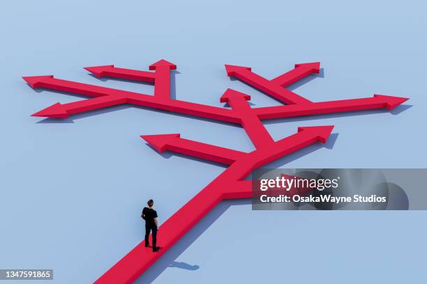 man standing on many-branched arrow, choice and decision - getting direction stock-fotos und bilder