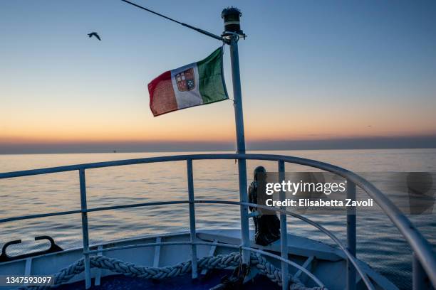 The Italian flag is seen aboard the fishing vessel, Levriero II, at sunset on October 18, 2021 in Rimini, Italy. According to a recent study released...
