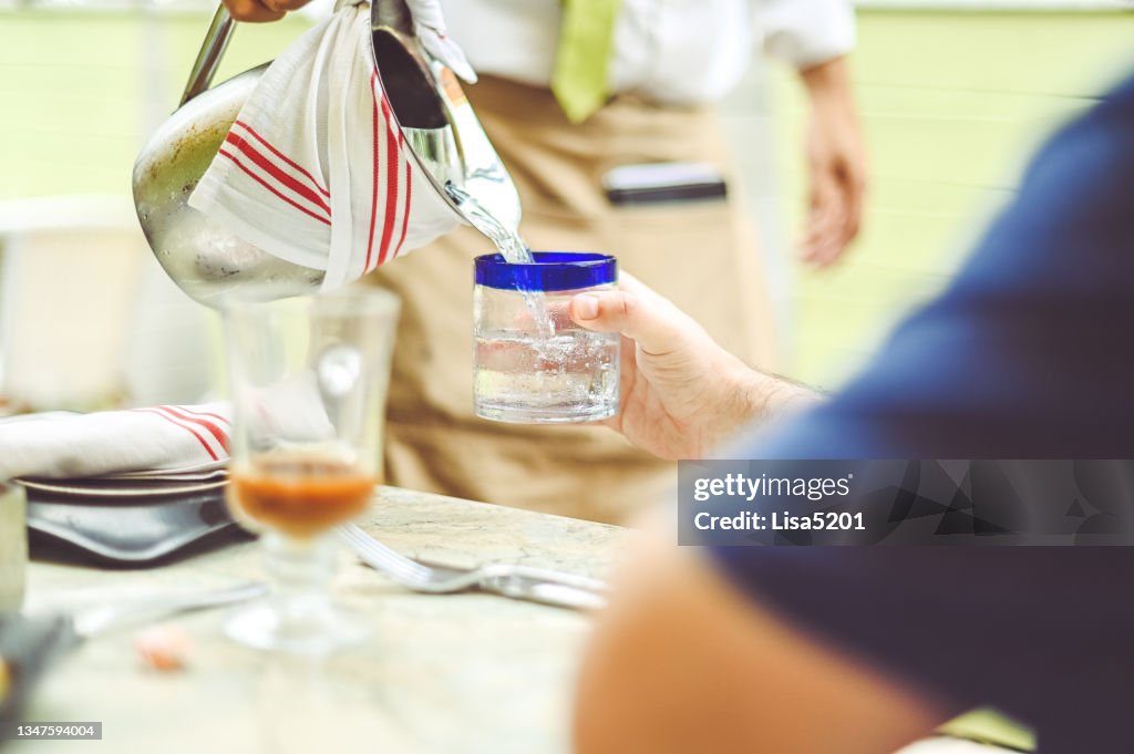 Waiter refills water glass at a restaurant