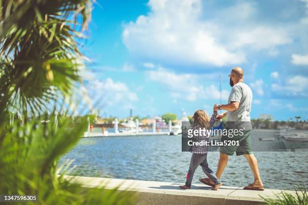 father and daughter walk along the waterfront in sunny tropical location - west palm beach stock pictures, royalty-free photos & images