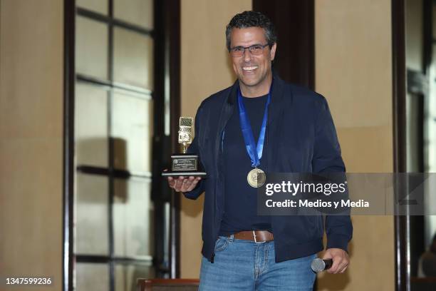 Marco Antonio Regil poses for photo with 'Micrófono de Oro' award during a press conference related to the 10 million downloads of his podcast at...