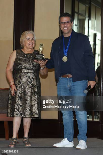 Rosalía Buaun gives the 'Micrófono de Oro' to Marco Antonio Regil during a press conference related to the 10 million downloads of his podcast at...