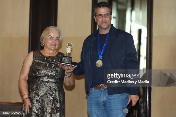 Rosalía Buaun gives the 'Micrófono de Oro' to Marco Antonio Regil during a press conference related to the 10 million downloads of his podcast at...
