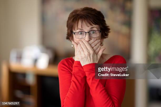 woman indoors covering her mouth - hand voor de mond stockfoto's en -beelden