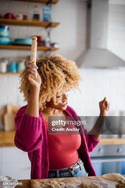 joyful woman singing and dancing while preparing christmas cookies in the kitchen - christmas music stock pictures, royalty-free photos & images