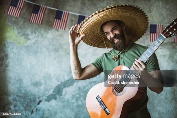 happy mariachi man playing a guitar on independence day. - sombrero stock pictures, royalty-free photos & images