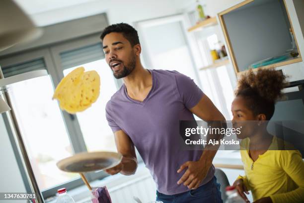 papa bringt der tochter bei, wie man pfannkuchen dreht. - pancake toss stock-fotos und bilder