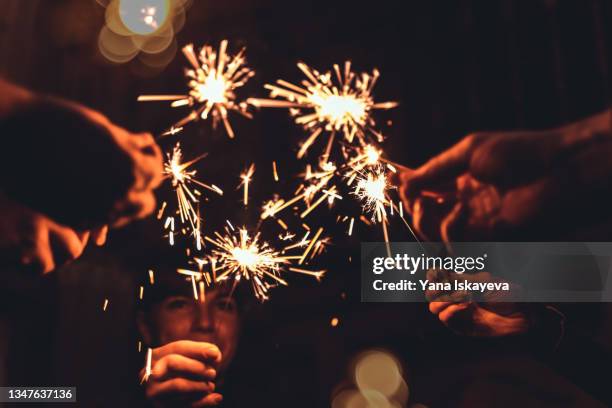 friends celebrating christmas and new year together holding firework sparkles - xmas together stock-fotos und bilder