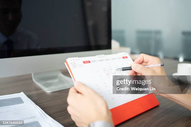 asian business man making marks on desk calendar - foto kalender stock-fotos und bilder