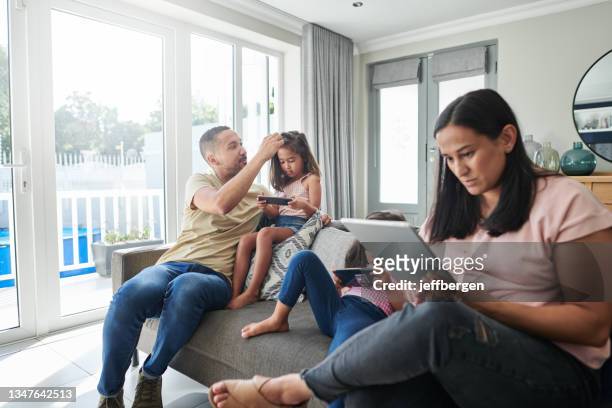 aufnahme einer jungen familie, die sich zu hause entspannt - family phone tablet stock-fotos und bilder