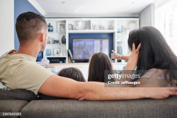 tiro de uma jovem família assistindo tv em casa - back shot position - fotografias e filmes do acervo