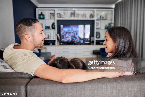 tiro de uma jovem família assistindo tv em casa - back shot position - fotografias e filmes do acervo