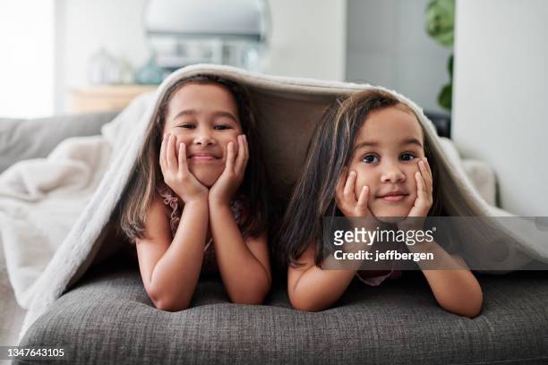 photo de deux petites filles allongées sur le canapé à la maison - blanket photos et images de collection