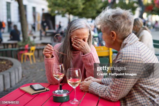 crying senior woman sitting with her friend in café. - male friends hanging out foto e immagini stock