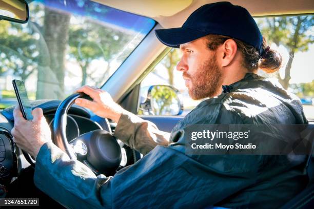 cropped shot of a handsome young male courier checking his cellphone for directions while making deliveries in his van - car studio shot stock pictures, royalty-free photos & images