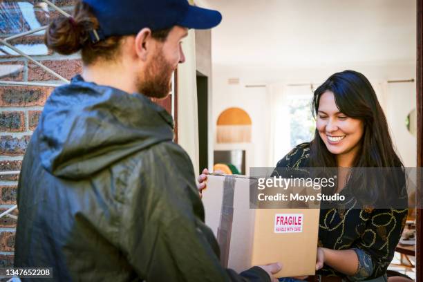 foto recortada de una atractiva joven que recibe su paquete en casa de un mensajero masculino - vendedor de puerta en puerta fotografías e imágenes de stock