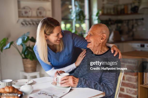 caregiver or healthcare worker visiting senior man at home. - asistencia de la comunidad fotografías e imágenes de stock