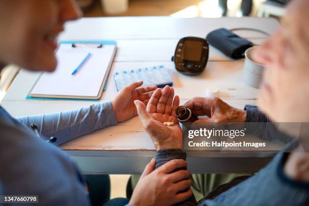 unrecognizable female caregiver talking to senior man indoors at home during home visit. - medicare photos et images de collection