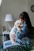 Owner of her old poodle breed dog has him hugged because of his great fatness and difficulty walking next to the window